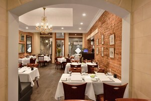 Un restaurant aux murs de briques, aux tables blanches et aux lustres.