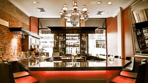 A bar area with a central island, bar stools, and a chandelier. - Hotel Bonaparte  (Montreal)