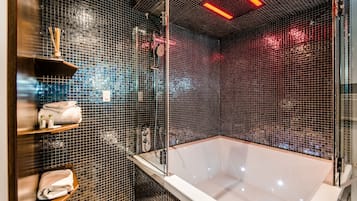 A modern bathroom with a large bathtub, a glass-enclosed shower, and shelves with toiletries.
