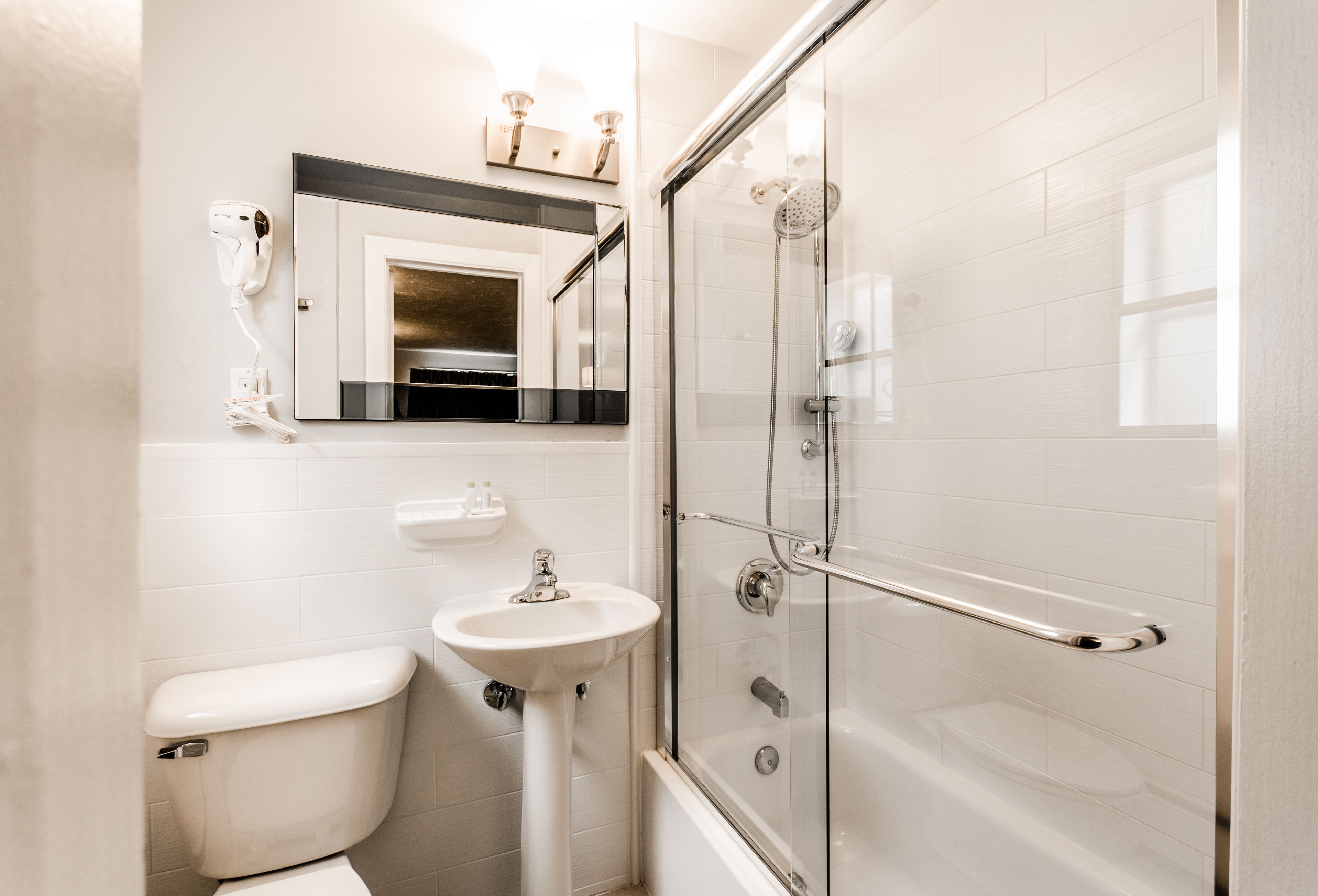 Un baño con inodoro, lavabo y ducha con mampara de vidrio.