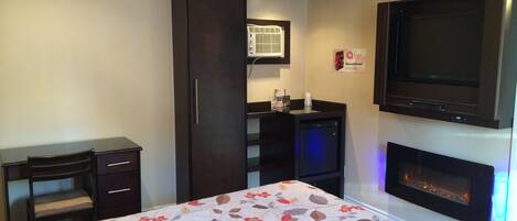 Une chambre d’hôtel équipée d’un lit, d’un bureau, d’une armoire, d’une télévision et d’une cheminée.