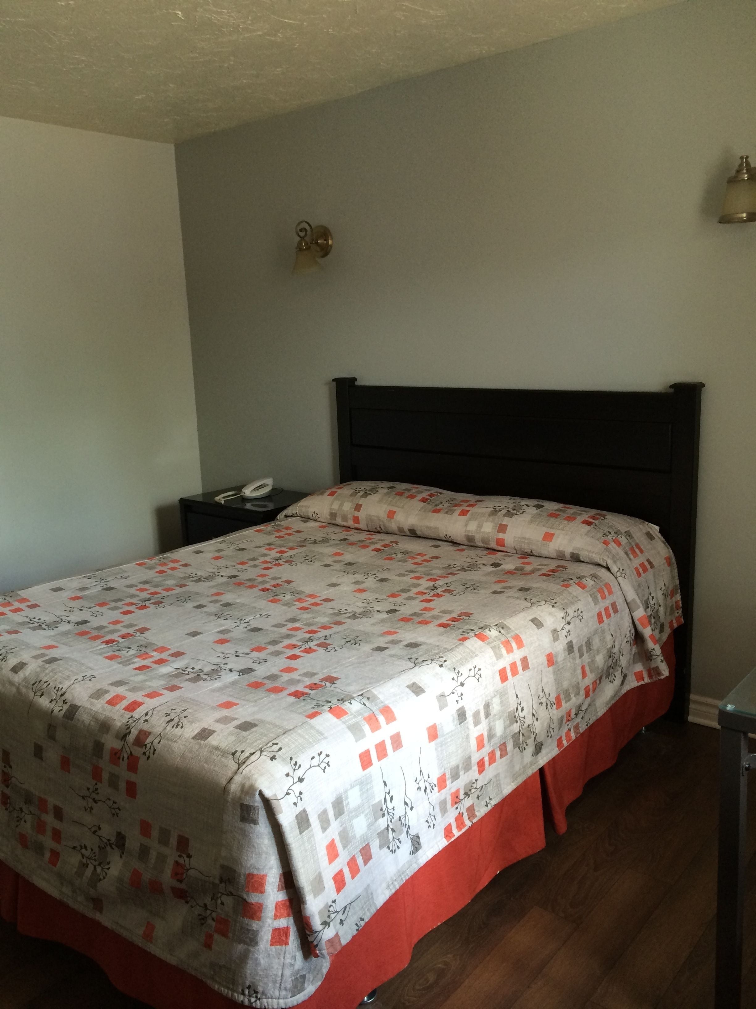 A bedroom with a bed, a nightstand, and a wall-mounted light fixture.