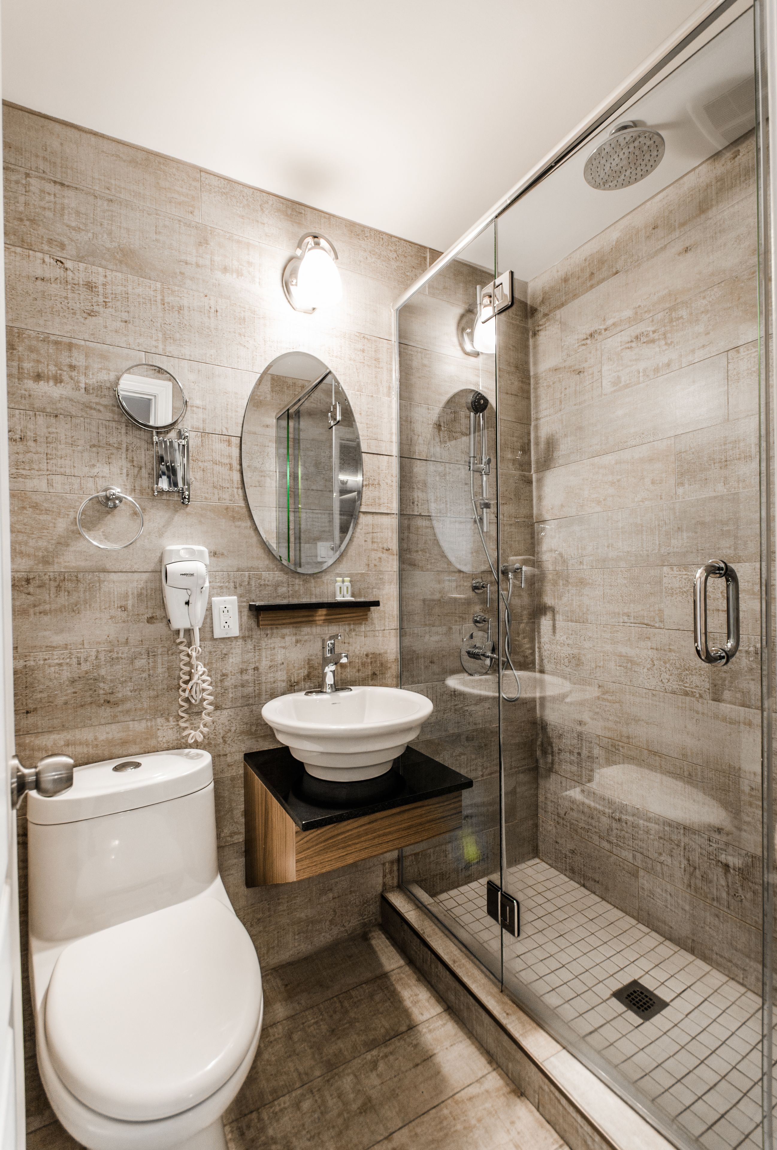 Un baño moderno con inodoro, lavamanos y ducha con mampara de vidrio.