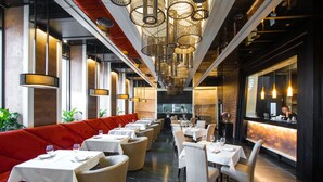 Ein modernes Restaurant mit hohen Decken, Pendelleuchten und einem zentralen Barbereich.