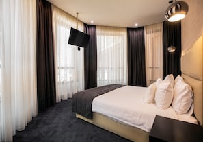 A hotel room with a bed, a flat-screen TV, and a large window with sheer curtains. - North Avenue by Stellar Hotels (Yerevan)