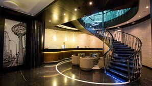 Eine moderne Lobby mit einer geschwungenen Treppe, einer Sitzecke und einem Empfangstisch.