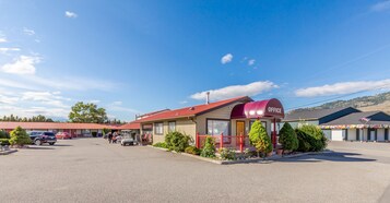 A small office building with a red awning labeled "OFFICE" and a parking lot with several cars.