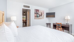 A hotel room with a large bed, a desk, a chair, and a TV on the wall. - Westridge Motor Inn (Osoyoos)