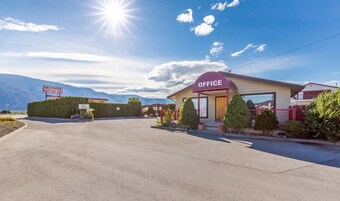A motel with a sign indicating 'Westridge Motor Inn' and 'Office' with a mountain backdrop.