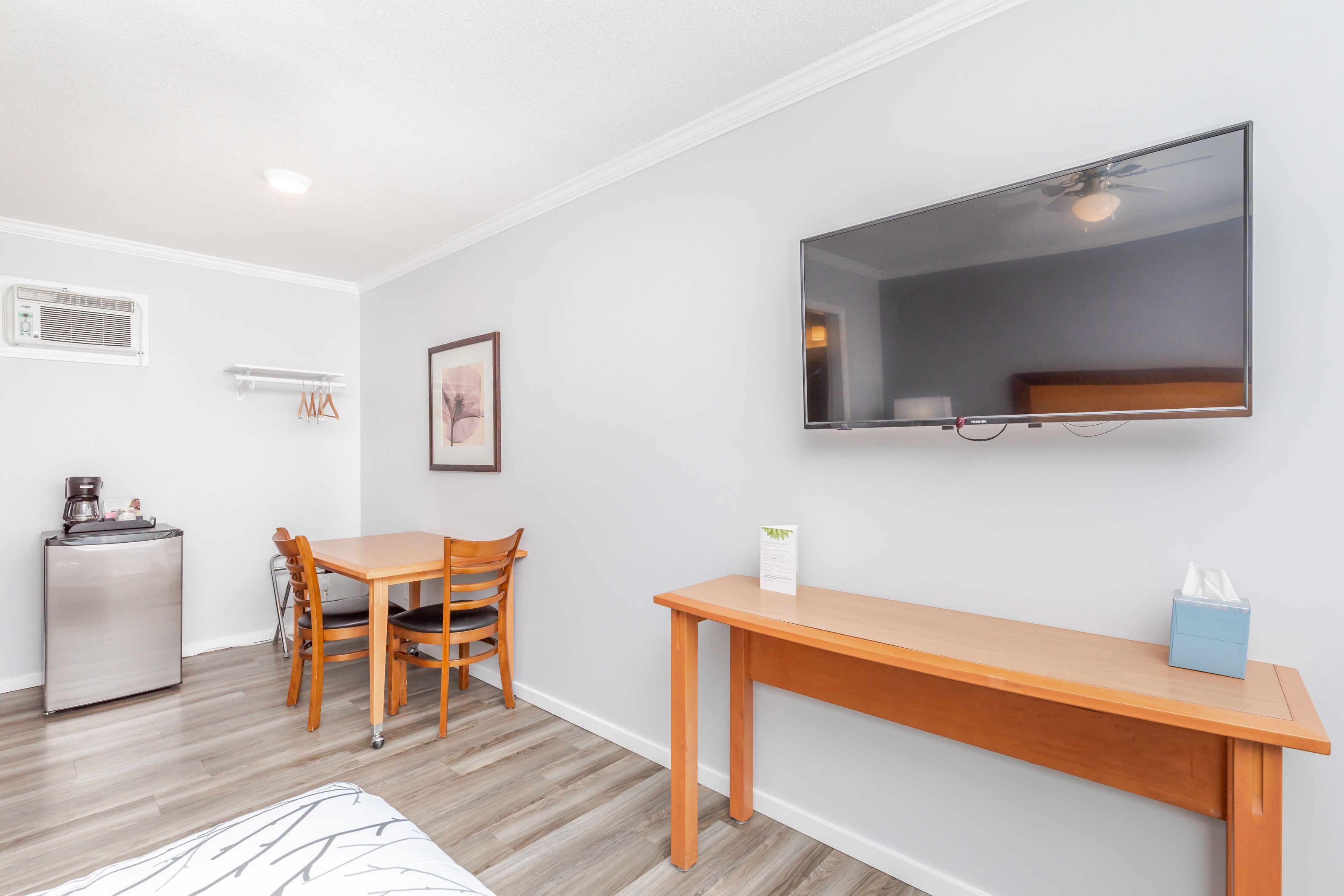 A compact living space with a kitchenette, a dining area, and a TV mounted on the wall.