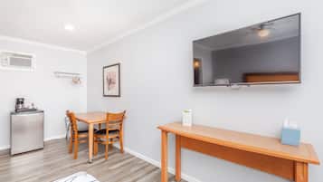 Un espacio habitable compacto con kitchenette, comedor y televisor montado en la pared.