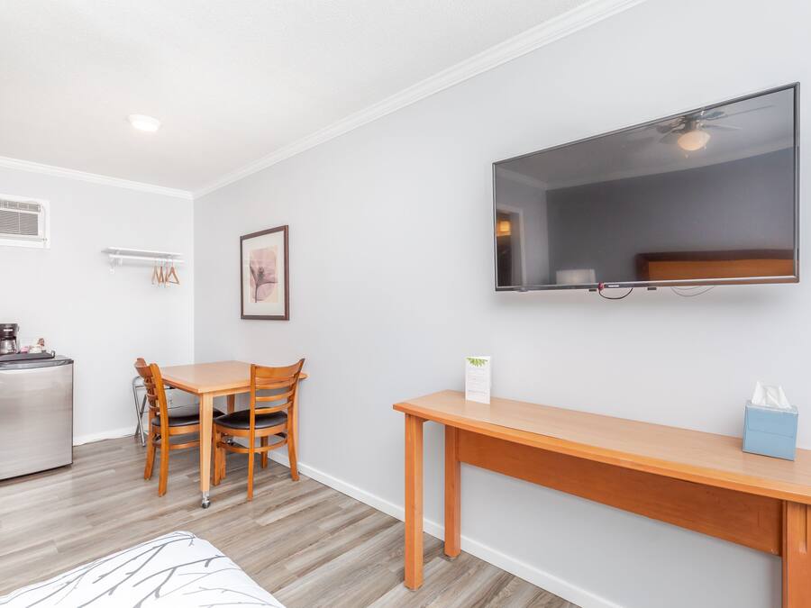 Un espacio habitable compacto con kitchenette, comedor y televisor montado en la pared.