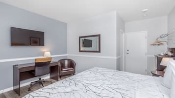 Una habitación de hotel con cama, escritorio, silla, televisión y armario.