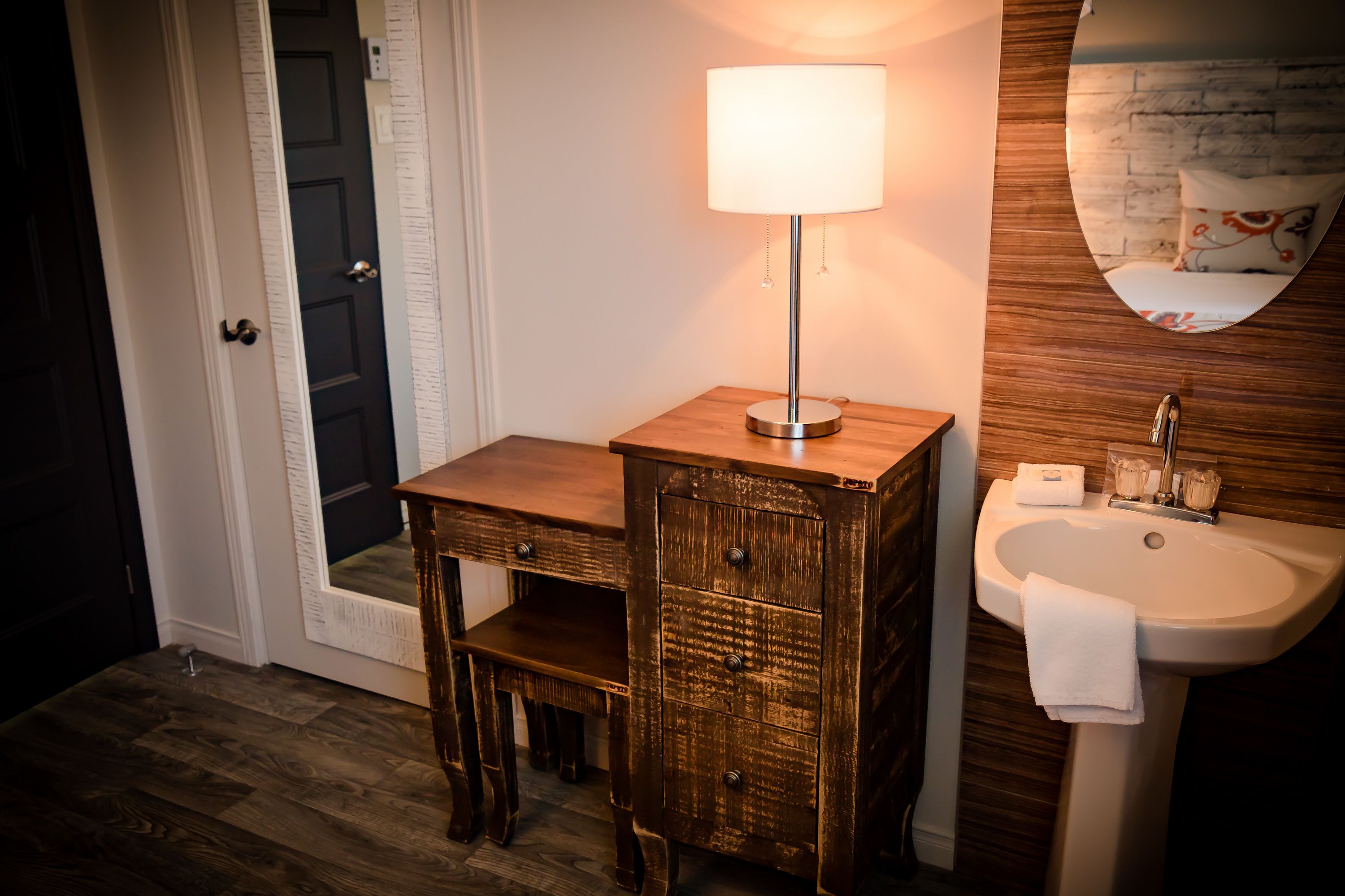 A bathroom with a wooden vanity, a white sink, and a mirror with a decorative frame.