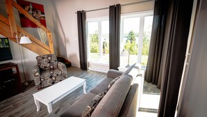 Una sala de estar con un sofá, un sillón estampado, una mesa de centro blanca y una escalera.