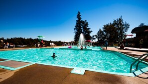 Una piscina con fuente de agua, rodeada de árboles y un cielo azul despejado.
