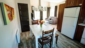 Una cocina moderna con una mesa de comedor, sillas de madera, un refrigerador y un sofá en la zona de estar.