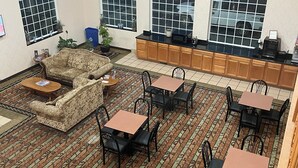 A spacious room with a patterned carpet, a sofa, and multiple tables and chairs.