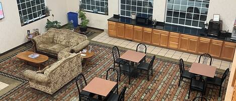Una habitación amplia con alfombra estampada, un sofá y varias mesas y sillas.