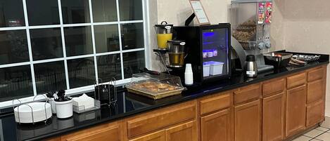 Eine Küche mit Kaffeemaschine, Kaffeeautomat und einer Auswahl an Gebäck.