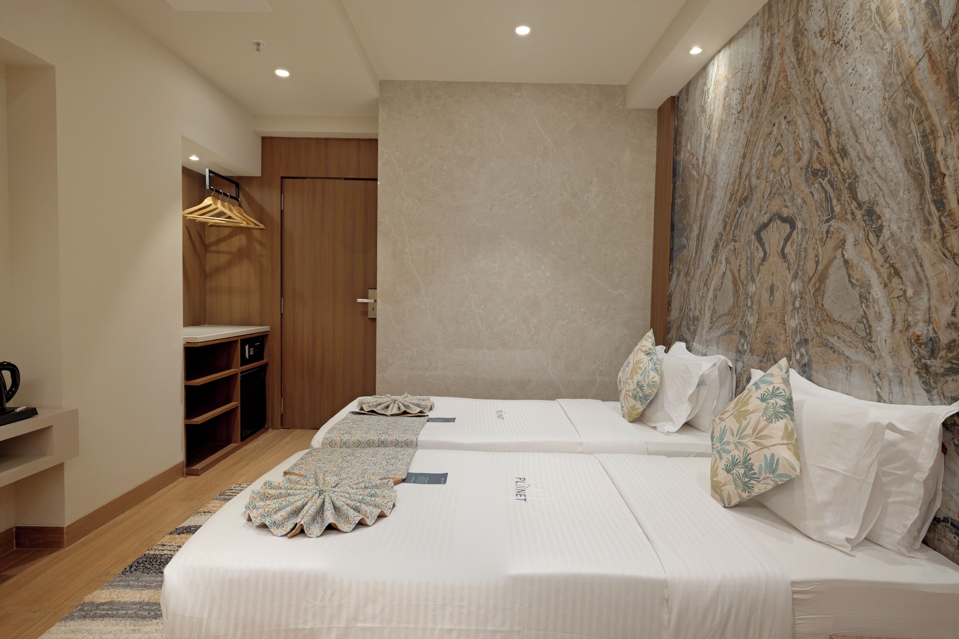 Ein Hotelzimmer mit zwei Betten, einem Kleiderschrank und einer Marmorwand.