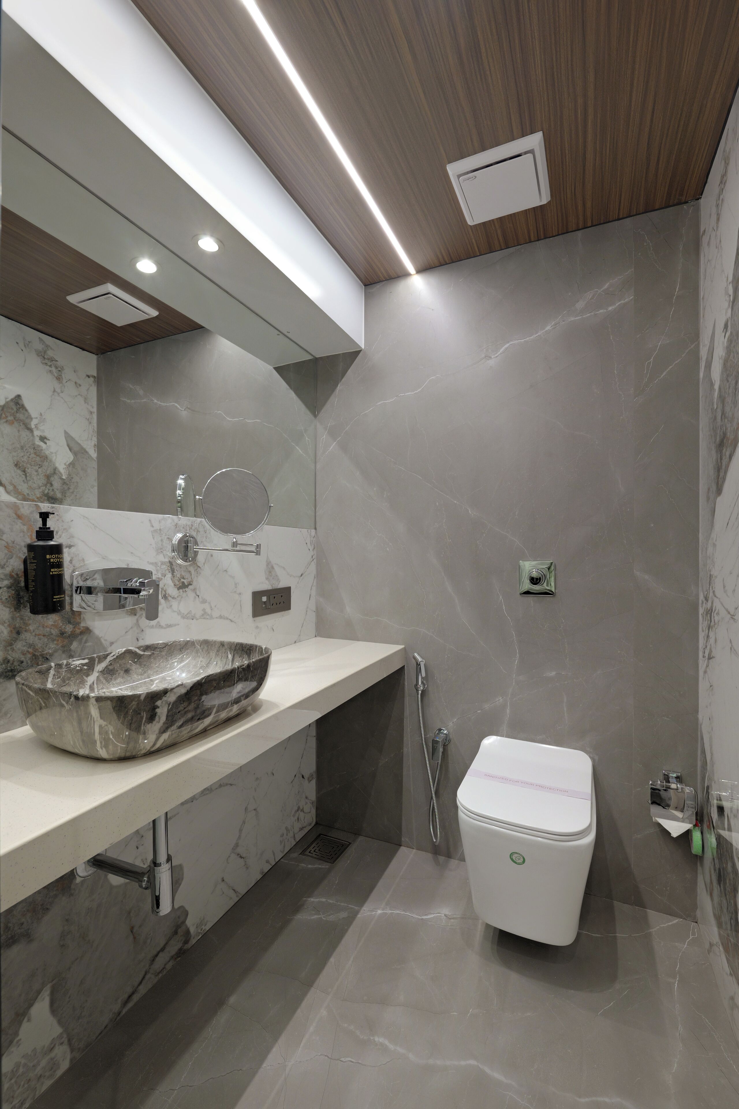 Un baño moderno con lavamanos de mármol, inodoro y zona de ducha.