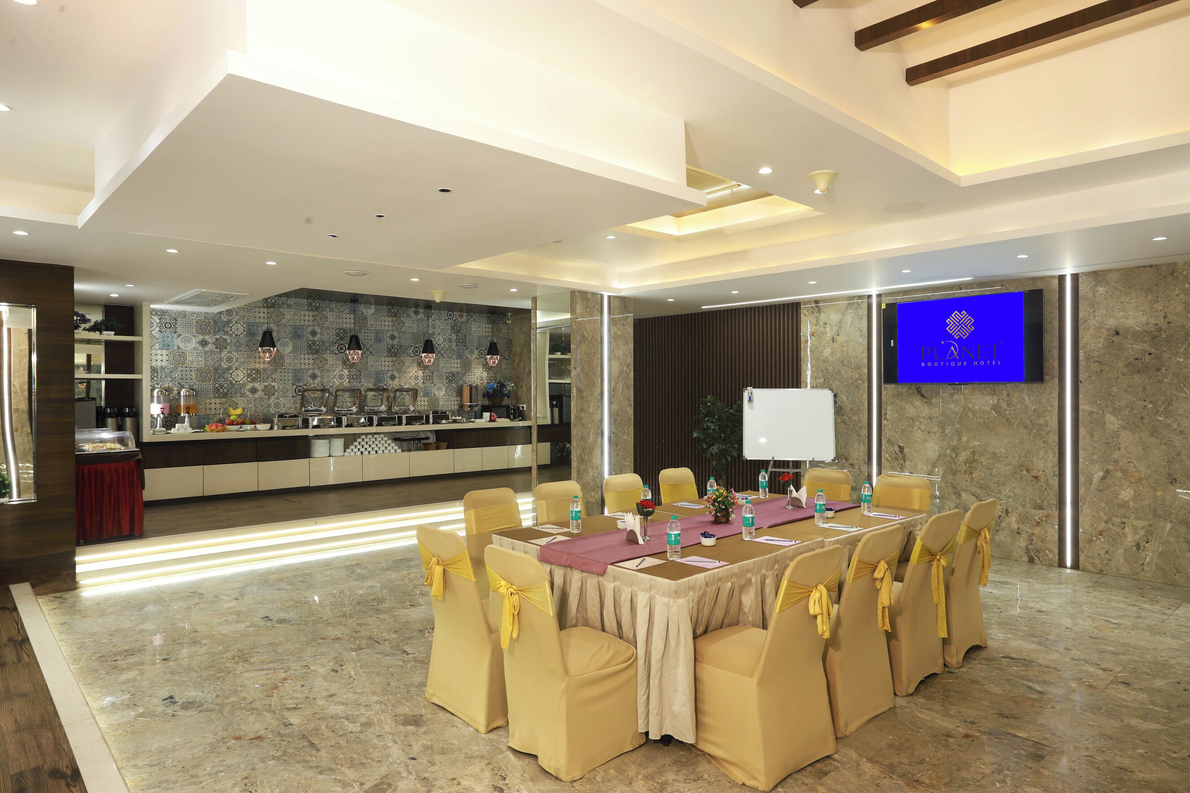 A conference room with a long table, yellow chairs, and a TV screen displaying a logo.