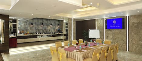 A conference room with a long table, yellow chairs, and a TV screen displaying a logo.