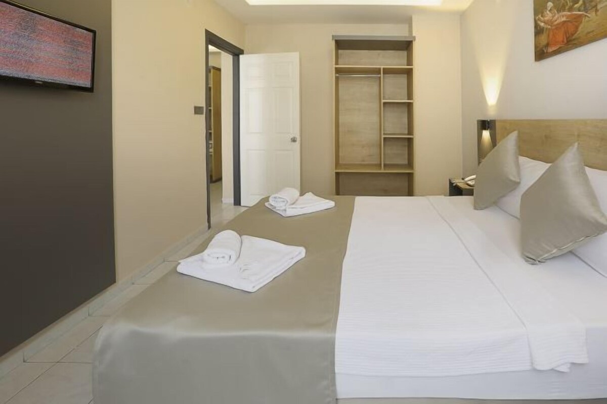 Una camera d'albergo con un letto, un armadio, una televisione e un quadro appeso al muro.