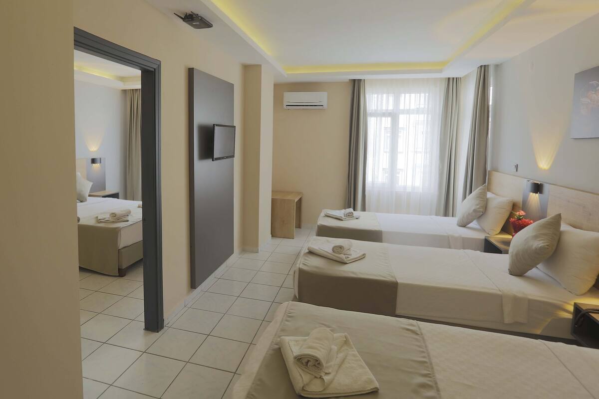 Une chambre d’hôtel avec deux lits, une télévision, un système de climatisation et une vue sur la ville grâce à de grandes fenêtres.