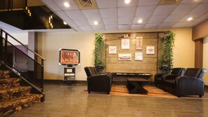 A lobby with a staircase, a fireplace, and a seating area with leather chairs and a coffee table.
