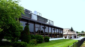 A modern building with a glass facade, outdoor seating area, and a well-maintained lawn.