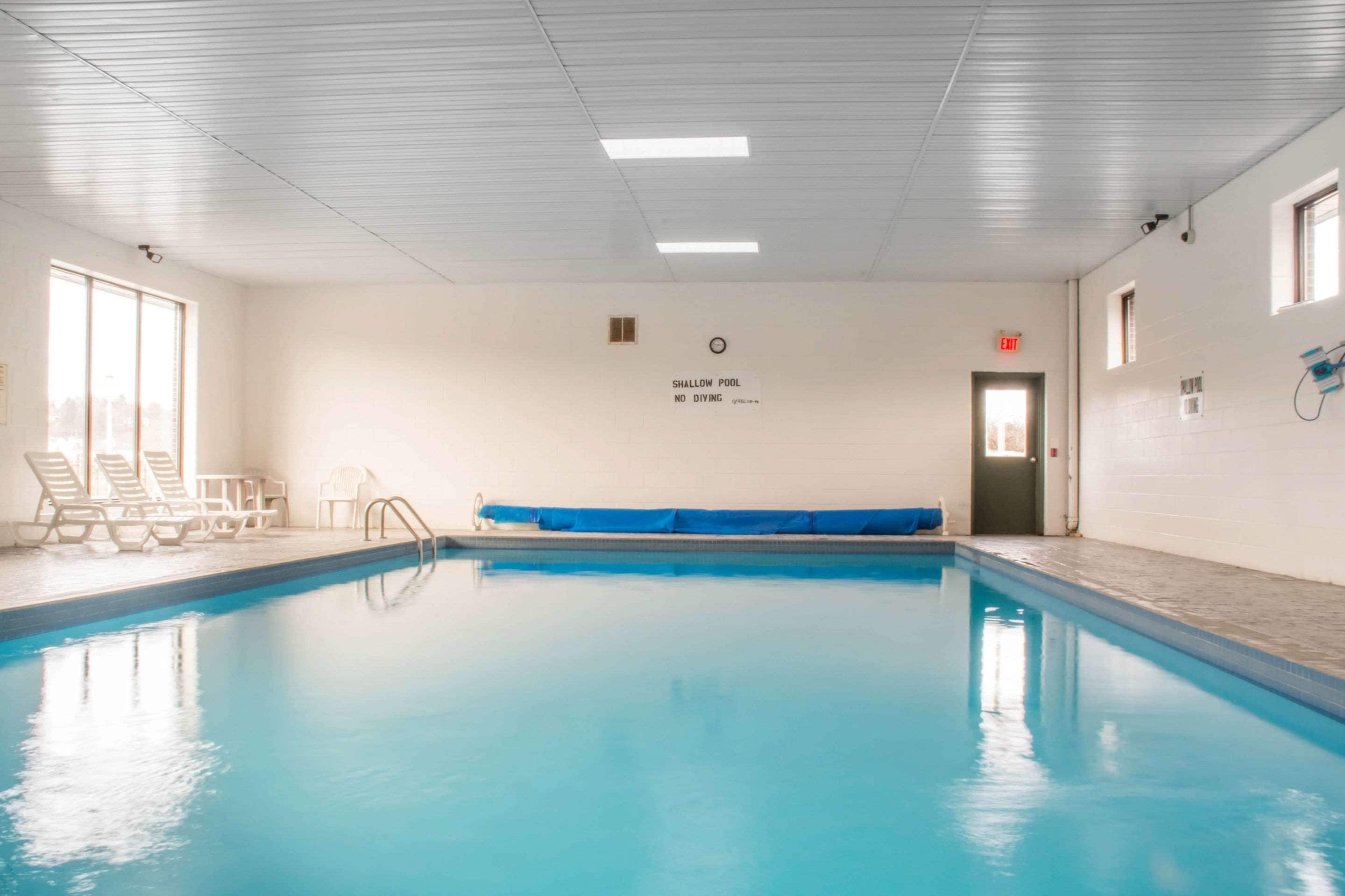 Ein Hallenbad mit flacher Zone, Liegestühlen und einer blauen Poolabdeckung.