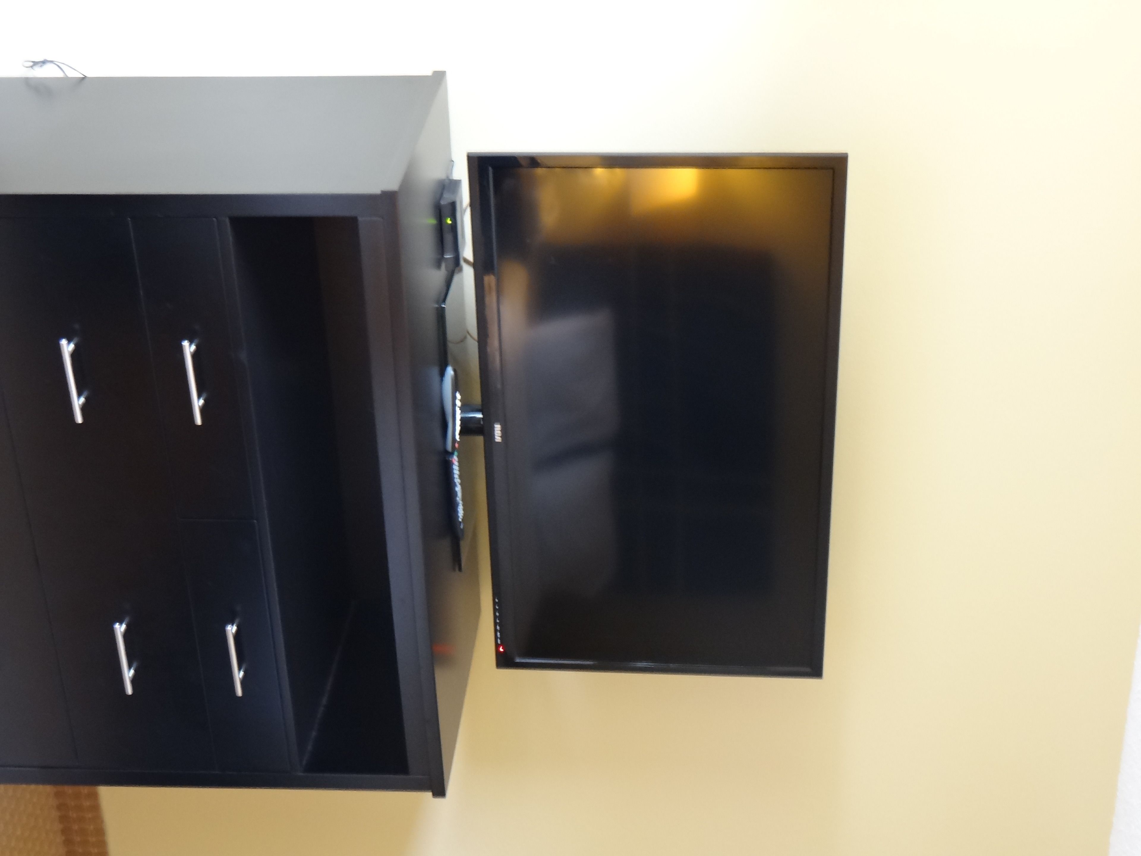 A wall-mounted black cabinet with a flat-screen TV and a small control panel.