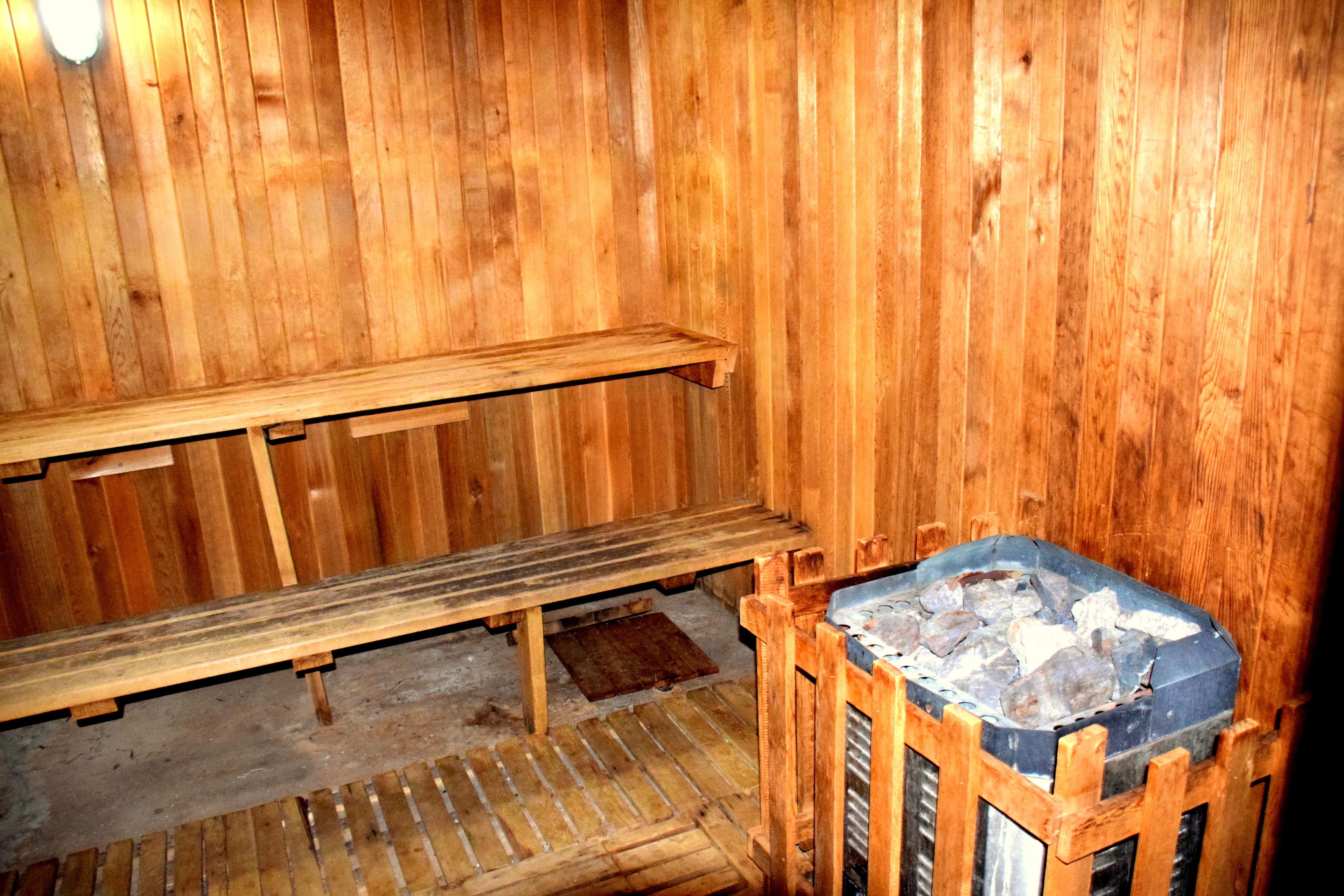 A wooden sauna room with benches and a stone heating element.
