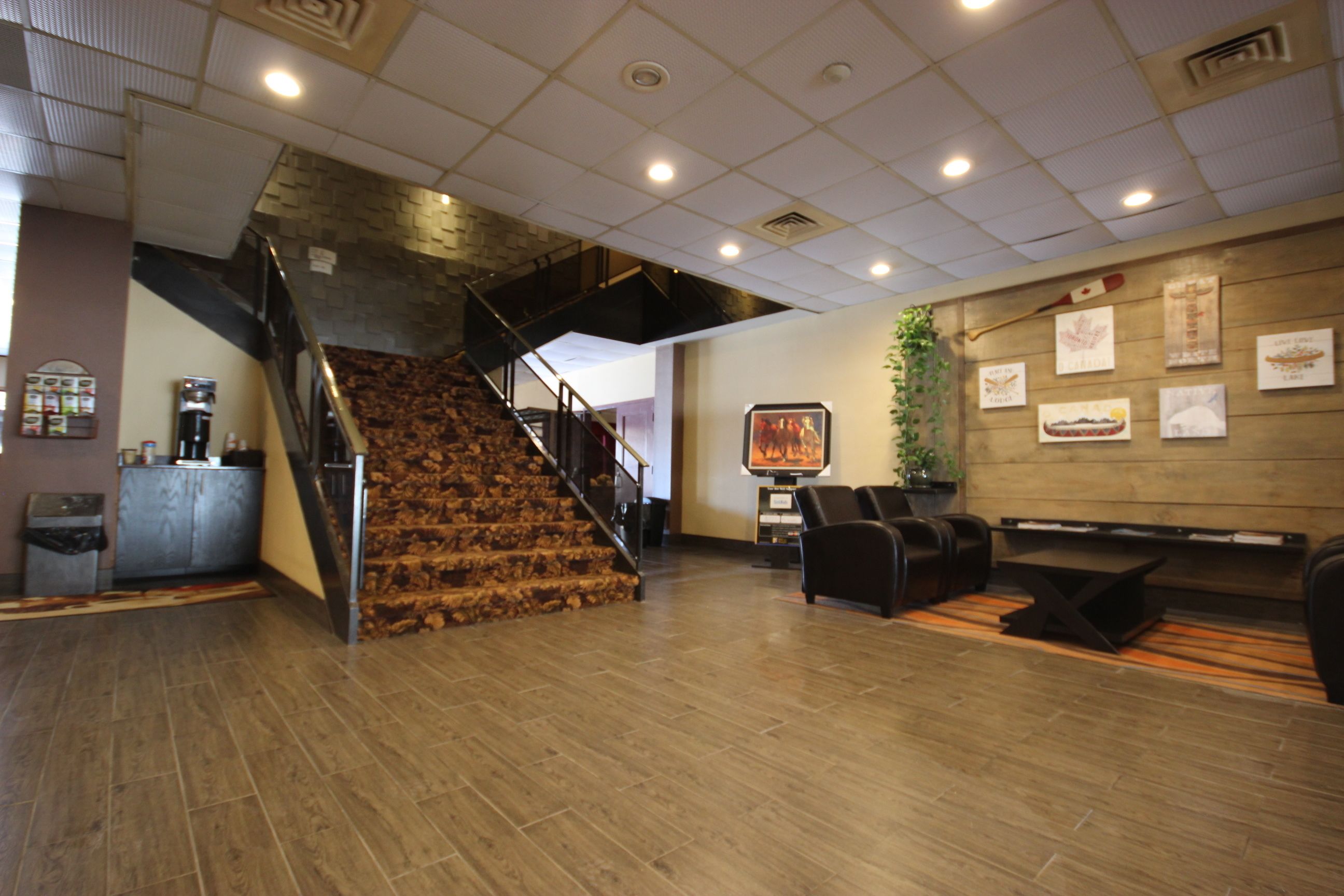 Un área de recepción con una escalera de madera, un mostrador de recepción y una pared decorada con cuadros.