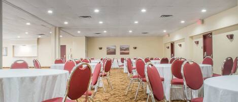 A conference room with rows of tables and chairs, carpeted floor, and ceiling lights.