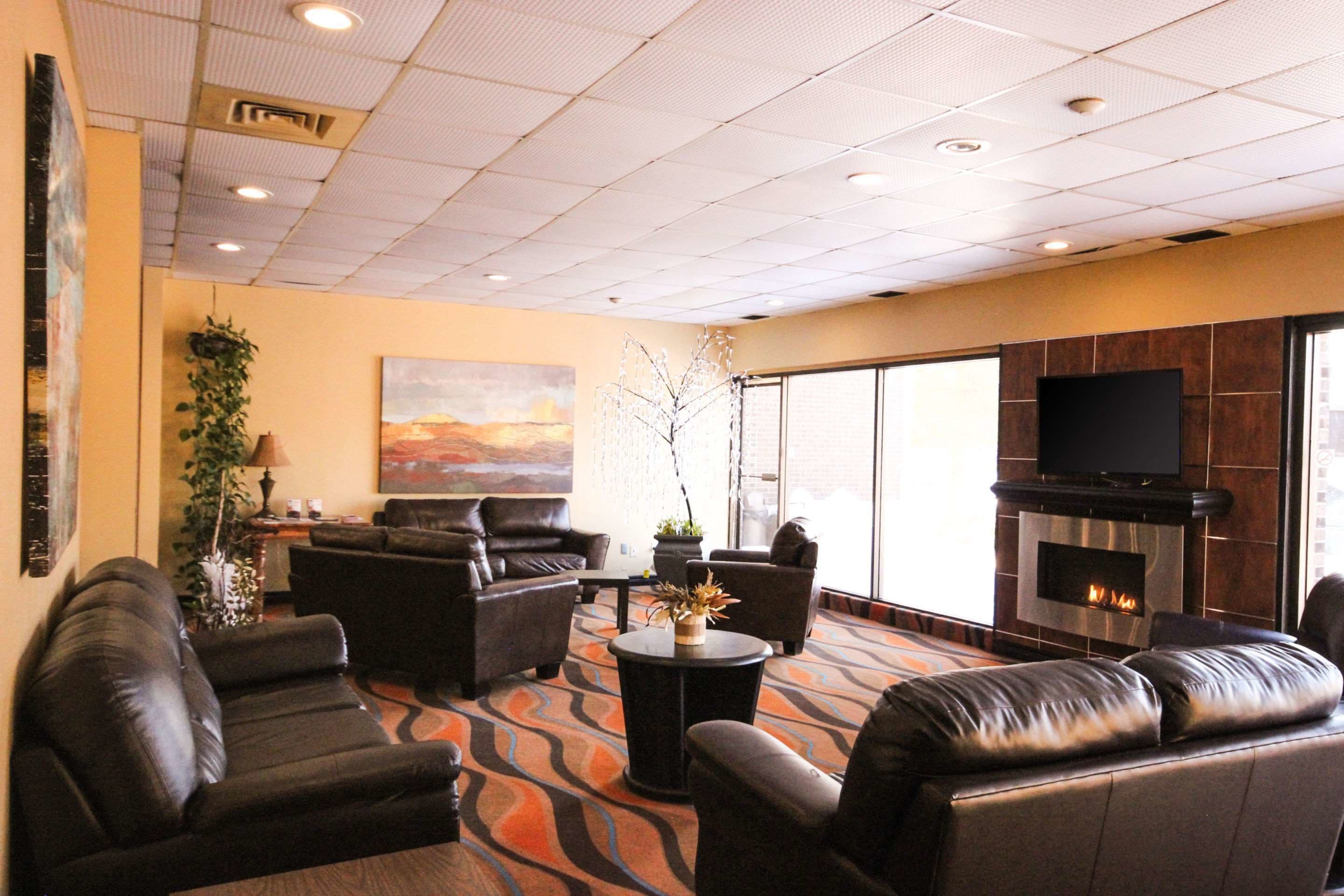 A spacious lounge with leather sofas, a flat-screen TV, a fireplace, and large windows.