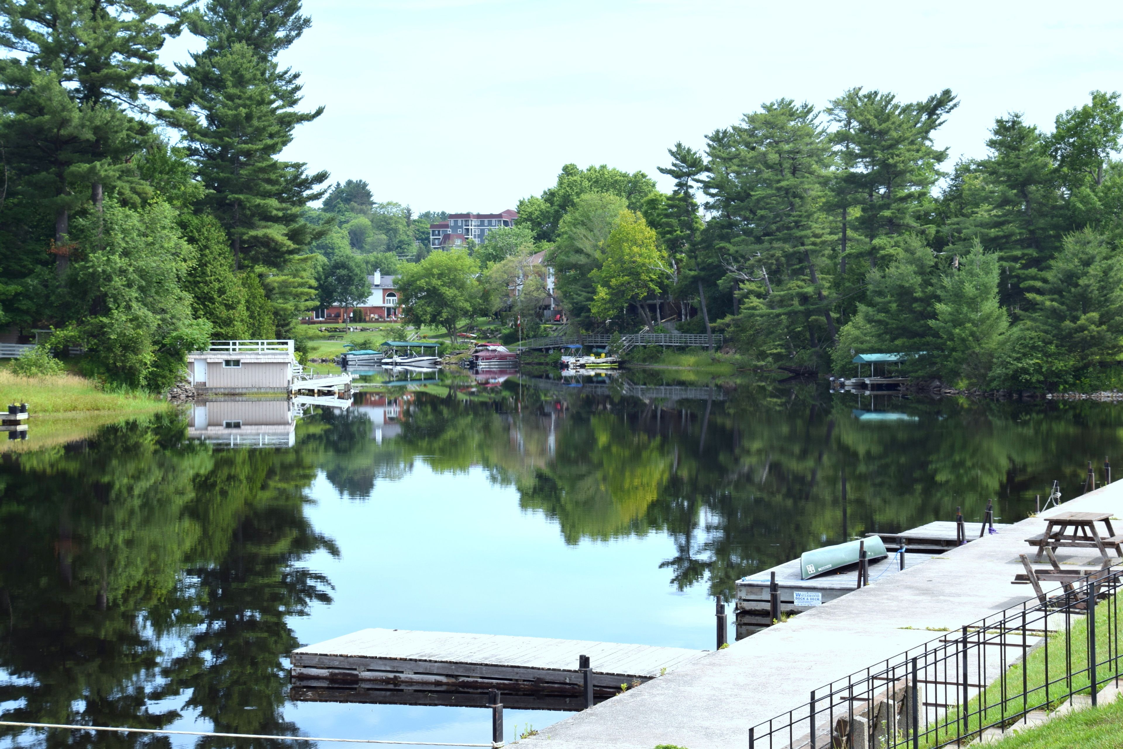 A calm lake with docked boats, a small building, and a picnic table.