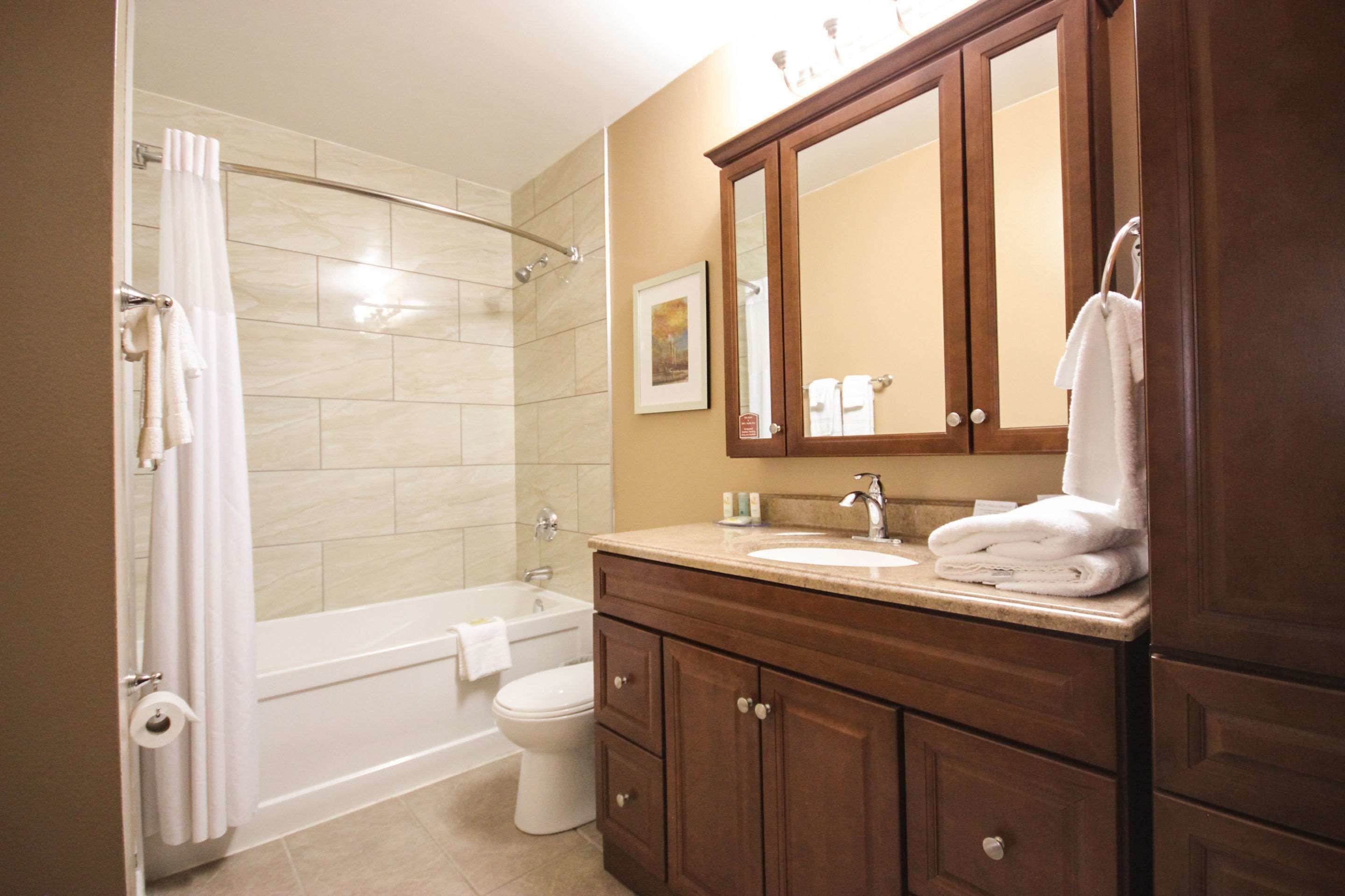 A bathroom with a bathtub, toilet, and vanity with a mirror.