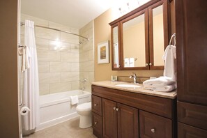 A bathroom with a bathtub, toilet, and vanity with a mirror.