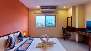 Camera d'albergo con un letto, una scrivania, una sedia, una TV e una finestra vista città.