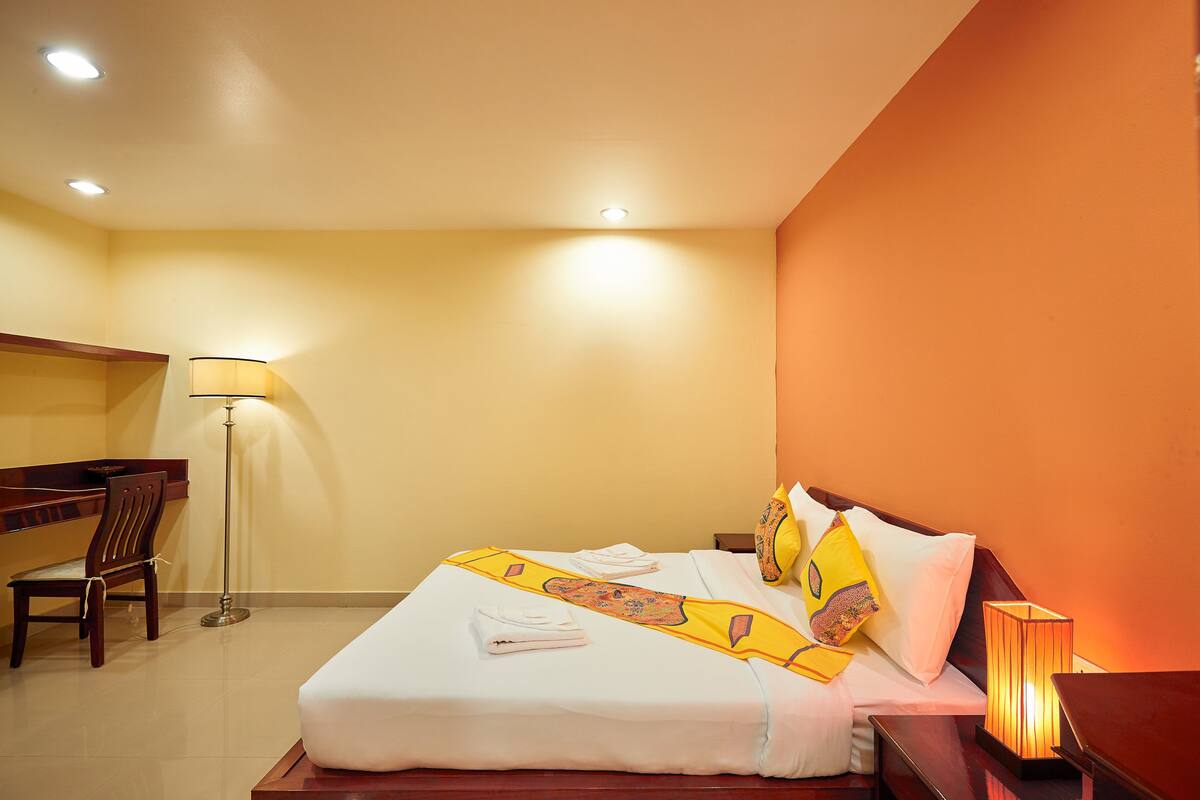 Habitación de hotel con cama, escritorio, silla y lámpara de pie.