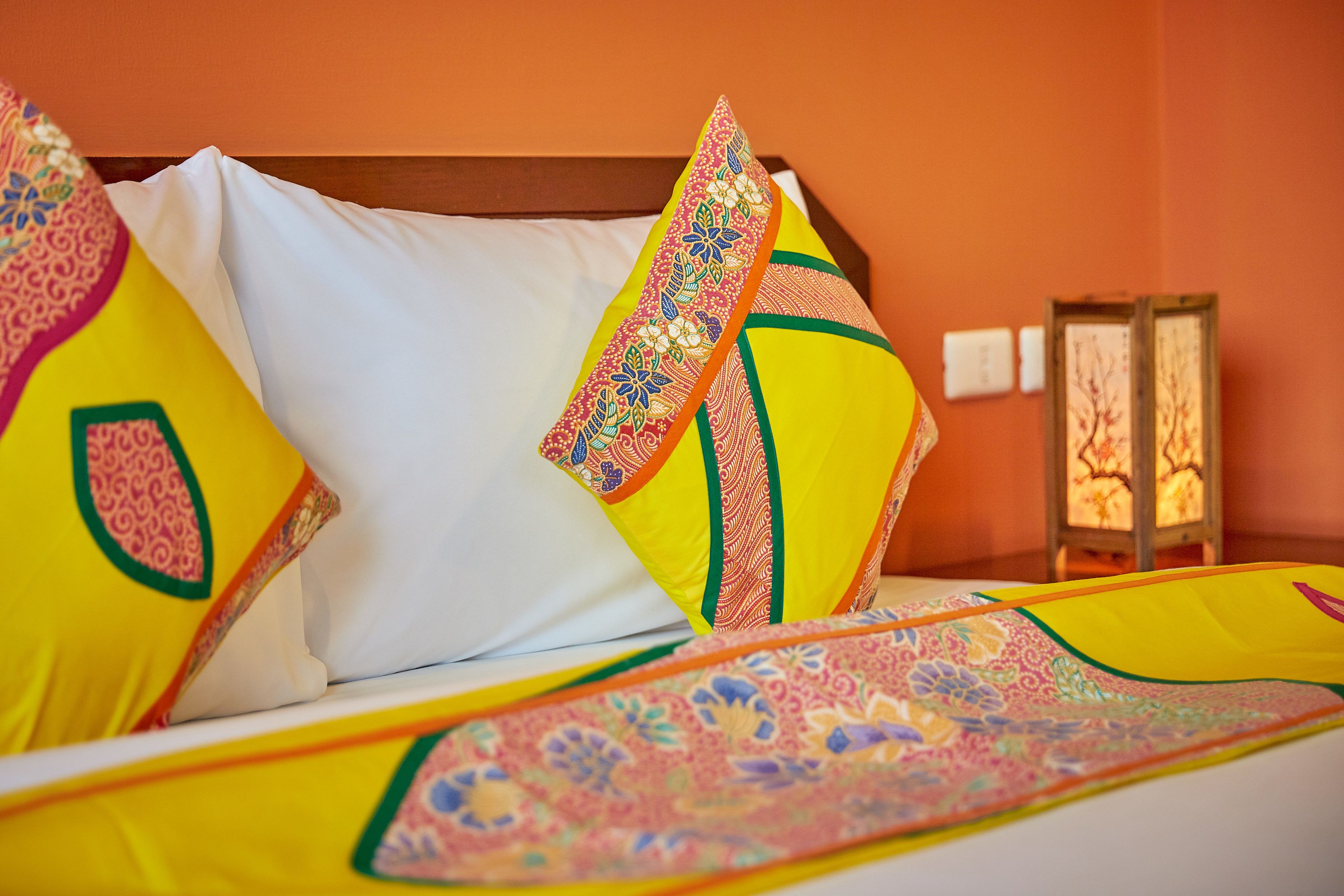 A bed with colorful pillows and a patterned bedspread.