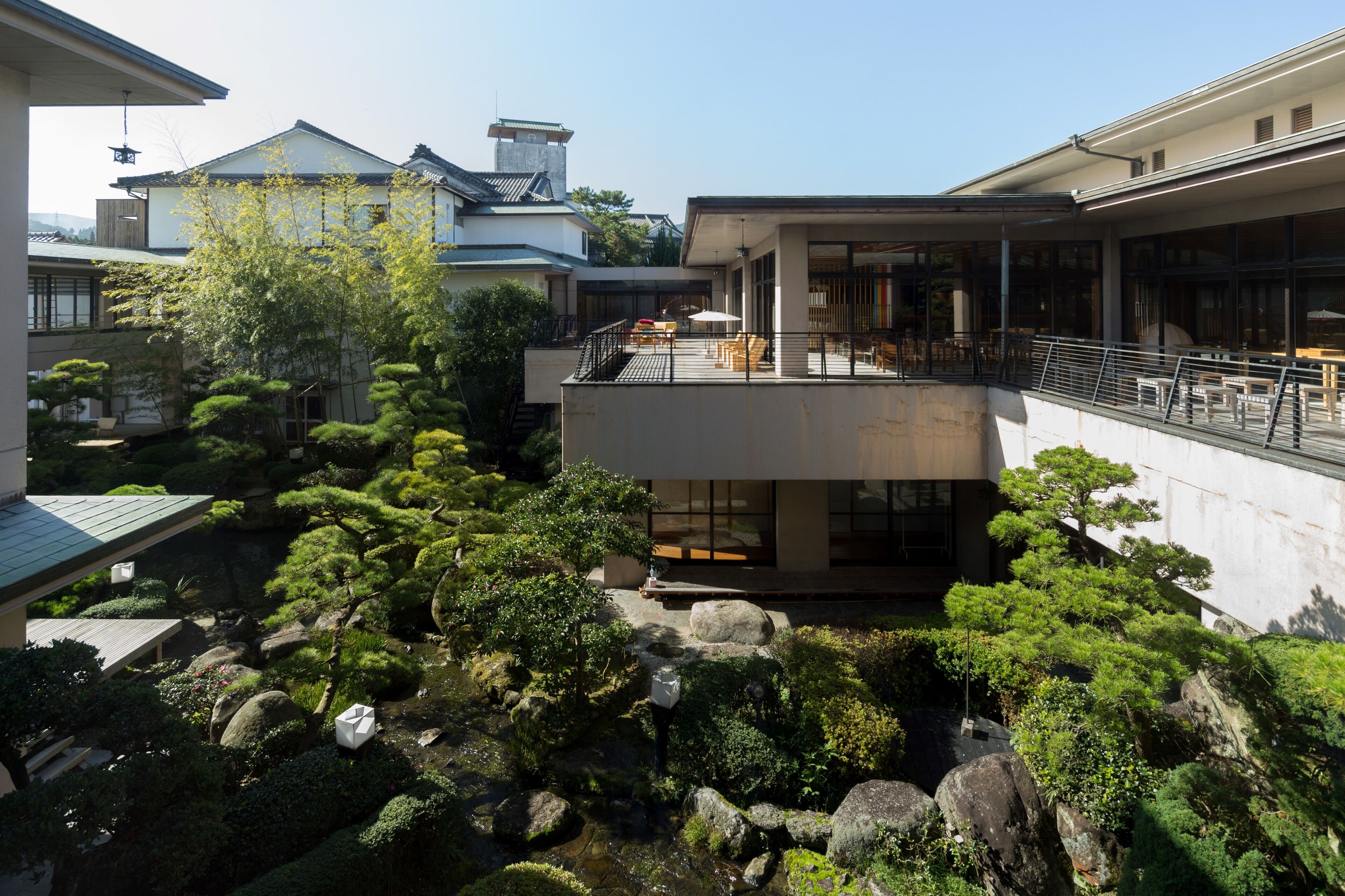 A modern building with a rooftop terrace, a koi pond, and traditional Japanese landscaping.