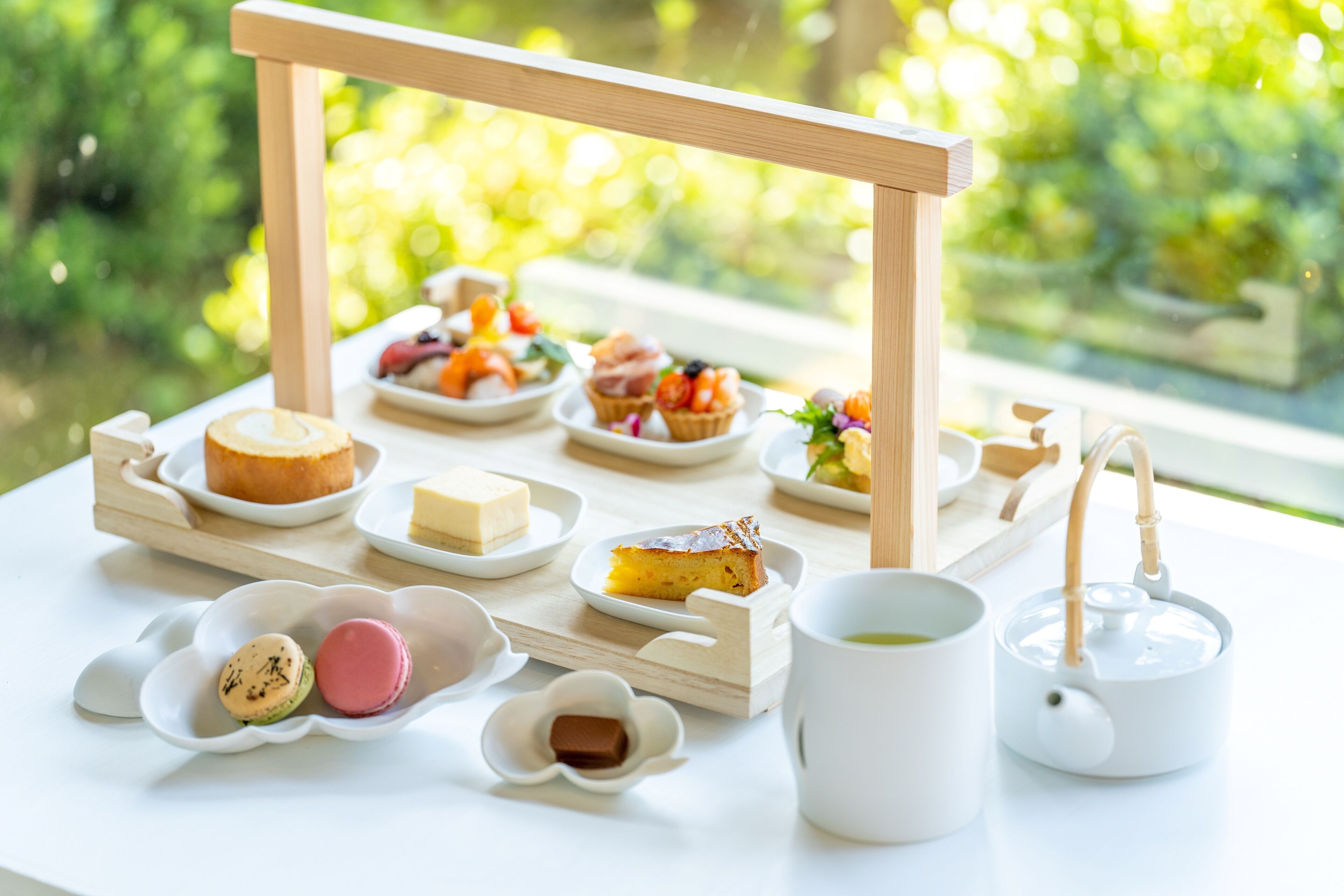 Una mesa dispuesta con diversas opciones de comida, incluyendo macarons, un pastel y una tetera.