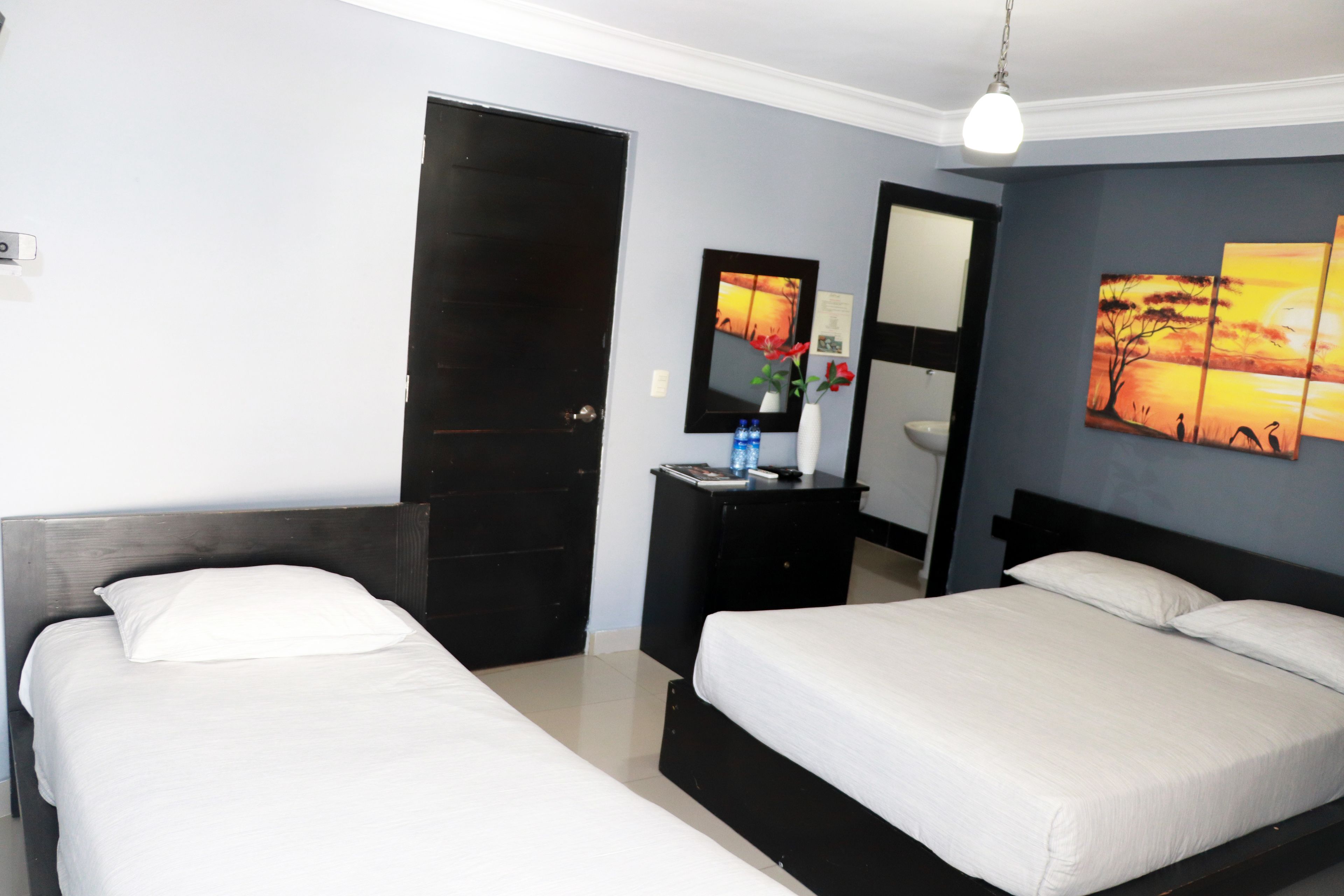 Een hotelkamer met twee enkele bedden, een dressoir, een spiegel en kunstwerken aan de muur.