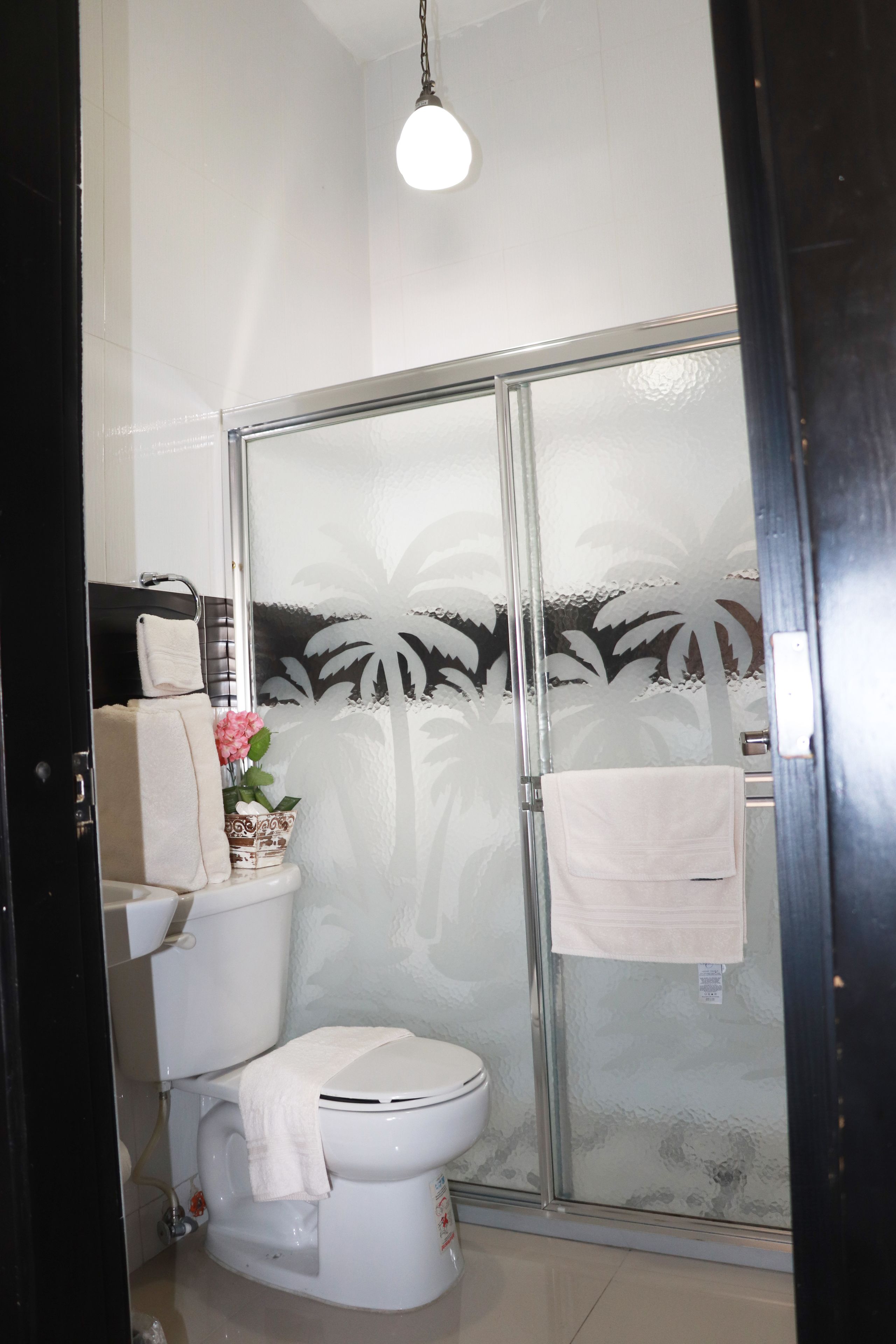 Un baño con inodoro, ducha con puerta de vidrio y barra para toallas.