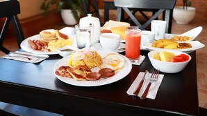 Una mesa de desayuno con platos de comida, entre ellos huevos, tortitas y tostadas.
