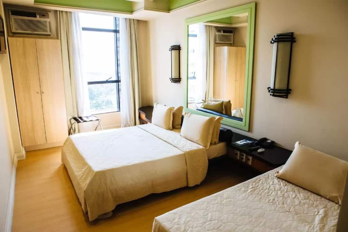A hotel room with two beds, a desk, a chair, and a large mirror.